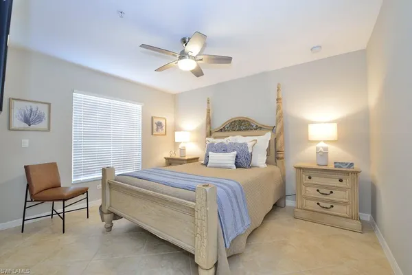 a bedroom with a bed a chair and a potted plant on the dresser