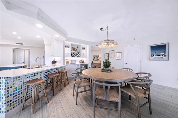a view of a dining room and livingroom with furniture wooden floor a rug a painting and a chandelier