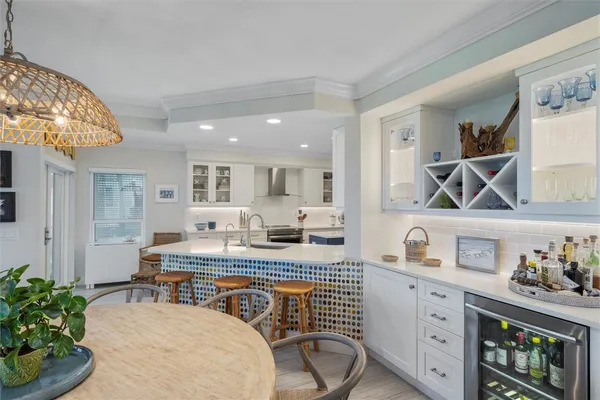 a very nice looking kitchen with granite countertop a white cabinets and chairs