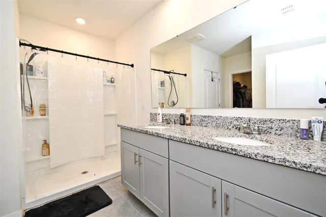 a bathroom with a granite countertop sink a mirror a shower and a bathtub