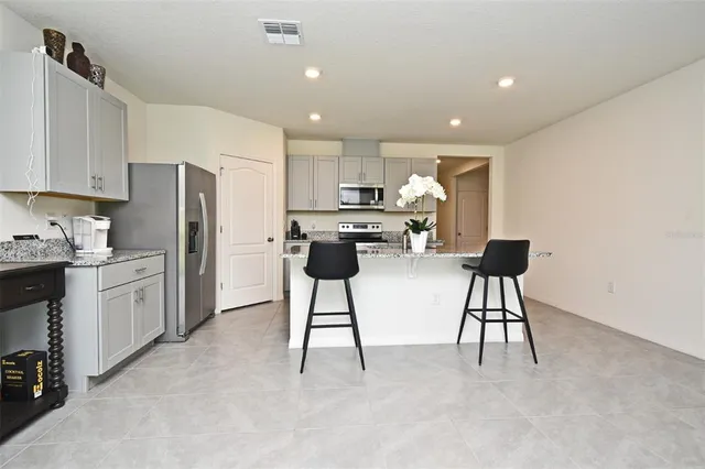 a kitchen with stainless steel appliances kitchen island granite countertop a refrigerator and a stove top oven