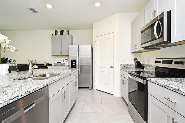 a kitchen with stainless steel appliances granite countertop a refrigerator and a stove top oven
