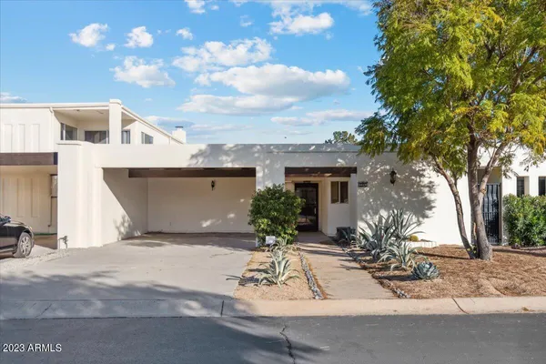 a view of a white house with a yard and potted plants