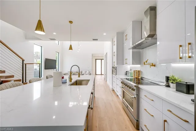 a large kitchen with stainless steel appliances a lot of white cabinets and a chandelier