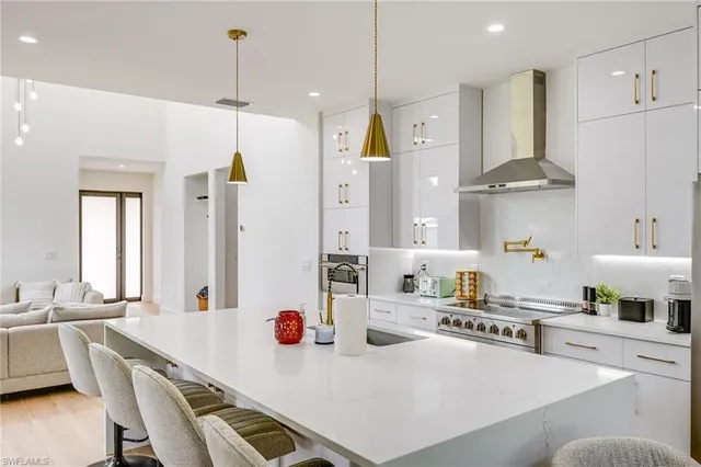 a kitchen with stainless steel appliances kitchen island granite countertop a sink a stove a refrigerator and white cabinets