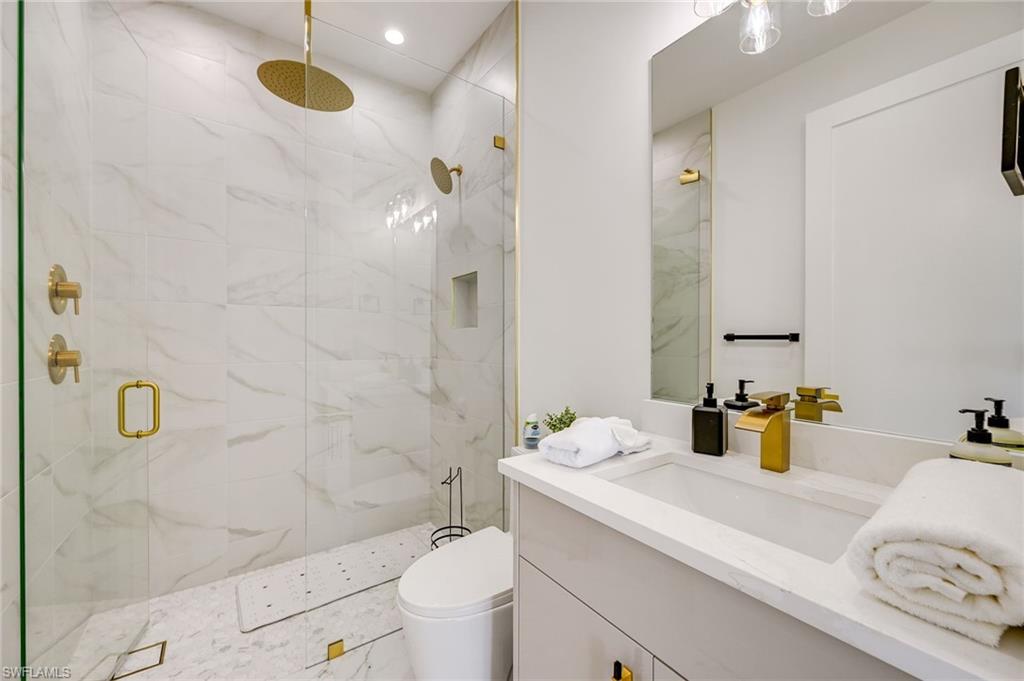 3384 Canal Street Naples, FL 34112 - Photo 26 of 34 a bathroom with a sink mirror vanity and toilet