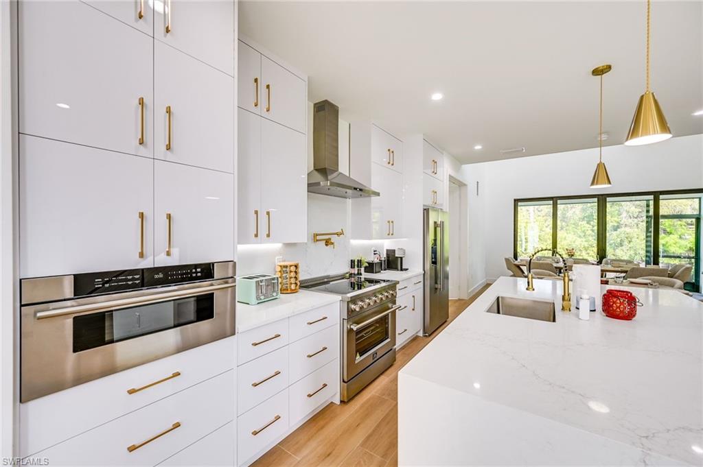 3384 Canal Street Naples, FL 34112 - Photo 7 of 34 a kitchen with stainless steel appliances kitchen island granite countertop a stove a sink and a refrigerator