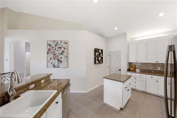 a kitchen with granite countertop white cabinets and stainless steel appliances