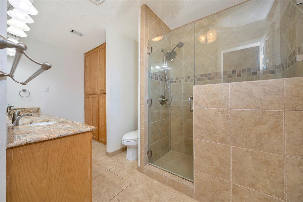 1761 Cynthia Lane Hurst, TX 76054 - Photo 28 of 40 a bathroom with a granite countertop sink a toilet and shower
