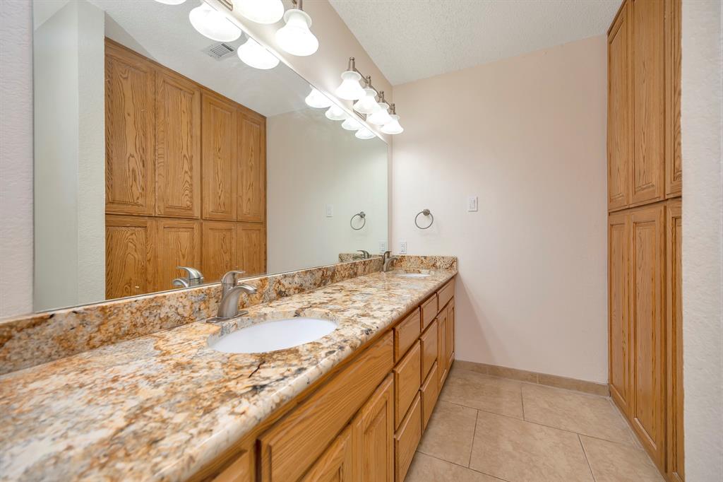 1761 Cynthia Lane Hurst, TX 76054 - Photo 29 of 40 a bathroom with a granite countertop sink a large mirror and vanity