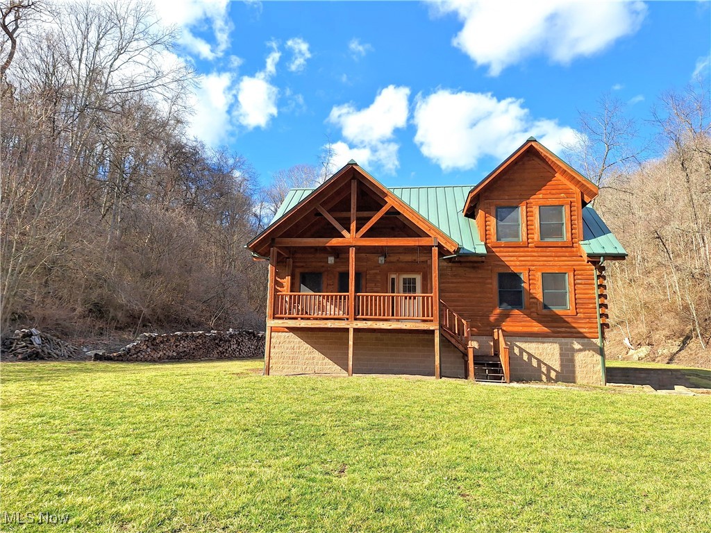 Rear view of property featuring stairway, a lawn, metal roof, a deck, and a standing seam roof