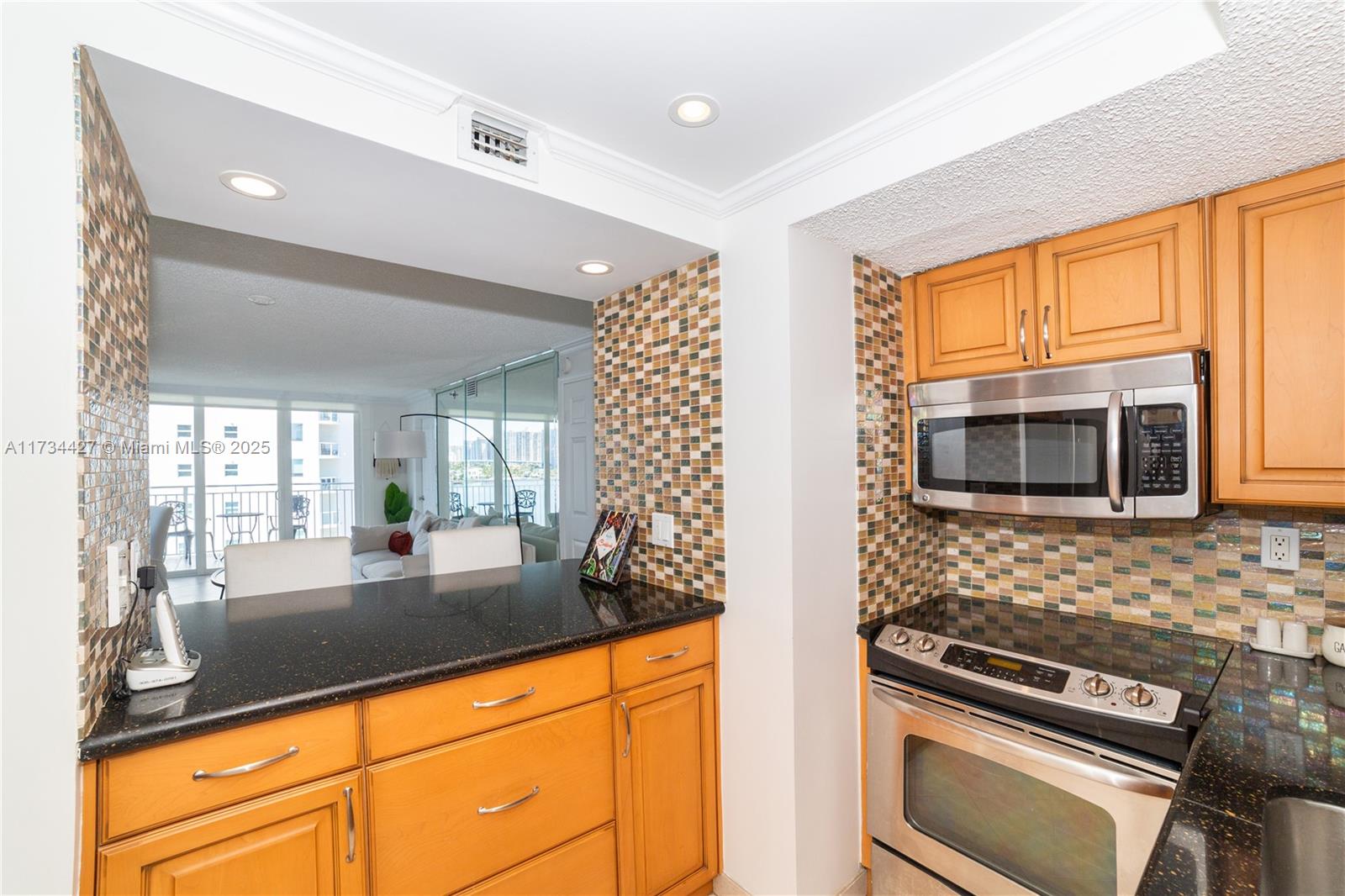 18000 North Bay Road, Unit 602 Sunny Isles Beach, FL 33160 - Photo 20 of 40 a kitchen with granite countertop a stove a sink and a microwave