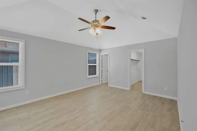 a view of empty room with wooden floor and ceiling fan
