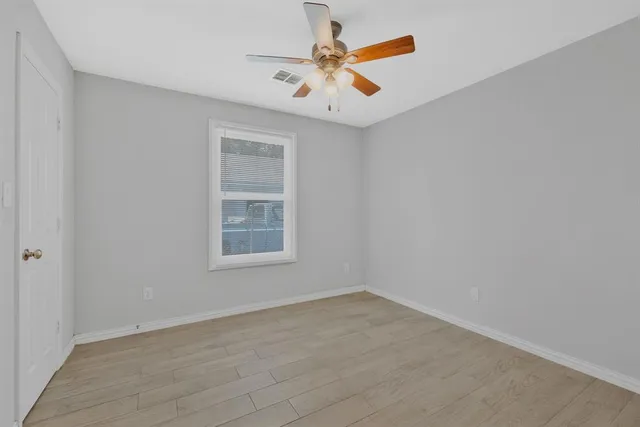 an empty room with a window and a ceiling fan