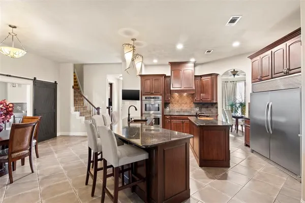 a kitchen with a dining table chairs refrigerator and microwave