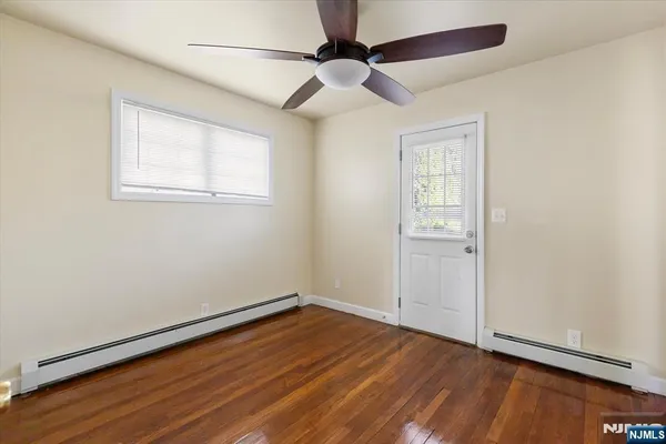 an empty room with wooden floor chandelier fan and windows