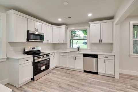 a kitchen with stainless steel appliances granite countertop white cabinets granite counter tops and a window