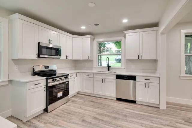a kitchen with stainless steel appliances granite countertop white cabinets granite counter tops and a window