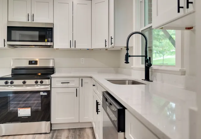 a kitchen with granite countertop a sink a stove and microwave