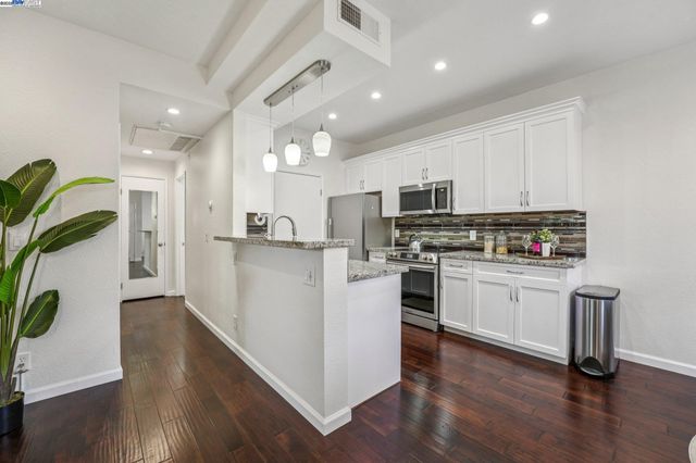 a kitchen with granite countertop a refrigerator stove top oven and sink