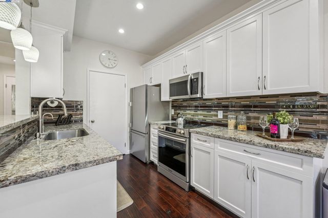 a kitchen with stainless steel appliances granite countertop a sink stove and refrigerator