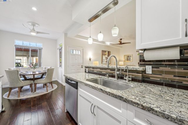 a kitchen with granite countertop a sink a counter space appliances and cabinets