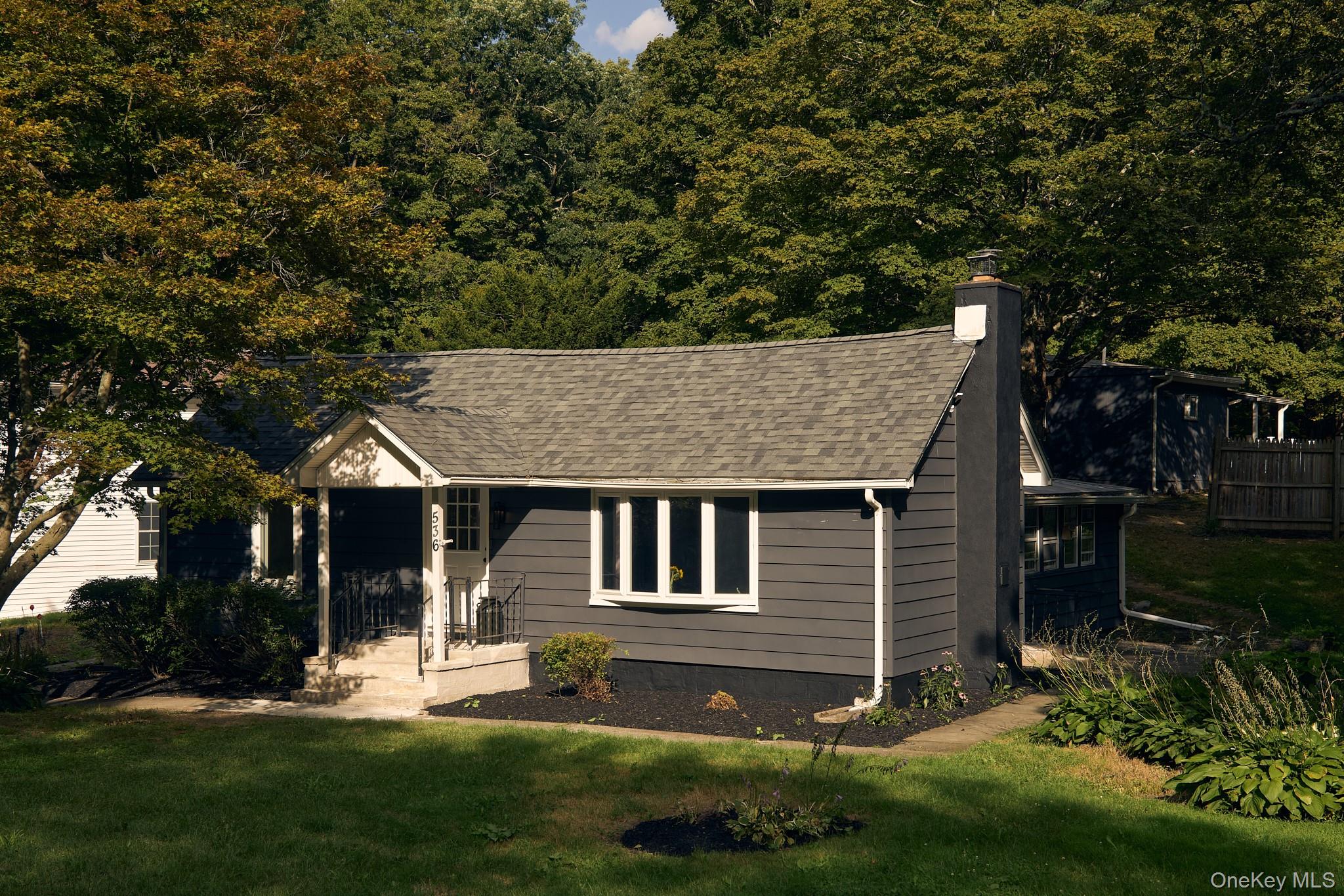 View of front of home featuring a front lawn, a chimney, and a shingled roof