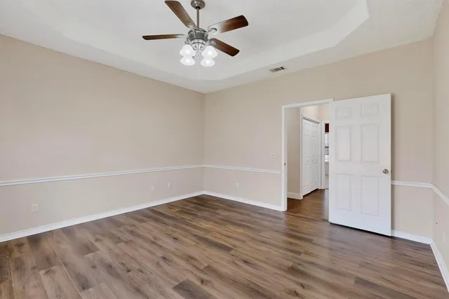an empty room with wooden floor and ceiling fan