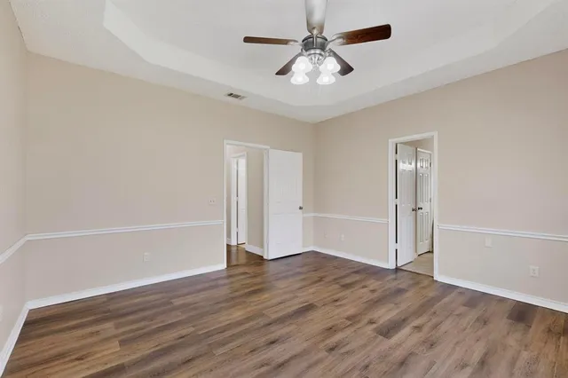 an empty room with wooden floor and ceiling fan
