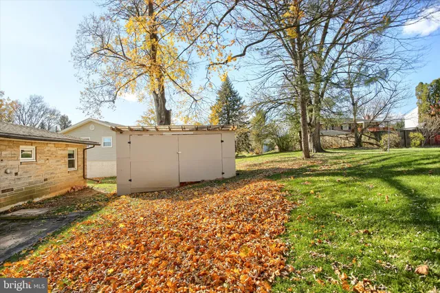 a backyard of a house with large trees and plants