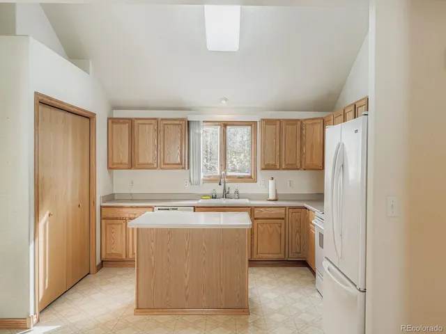 a kitchen with a sink a stove a refrigerator a center island and cabinets