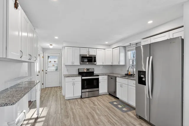 a kitchen with granite countertop white cabinets and stainless steel appliances