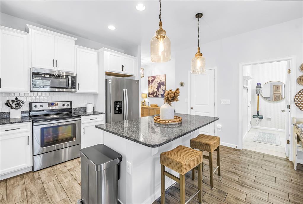 13229 Orca Sound Drive Riverview, FL 33579 - Photo 8 of 37 a kitchen with stainless steel appliances granite countertop a sink a stove a refrigerator and a dining table with wooden floor