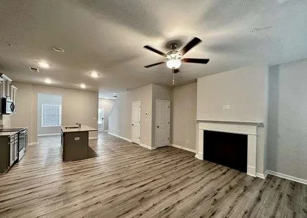 an empty room with wooden floor fireplace and windows
