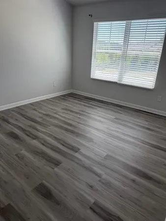 an empty room with wooden floor and windows