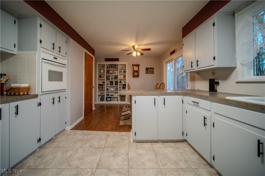 3447 Marian Road Ravenna, OH 44266 - Photo 11 of 35 Kitchen featuring a peninsula, backsplash, oven, and white cabinetry