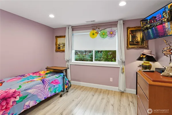a bedroom with a bed window and painting on the wall
