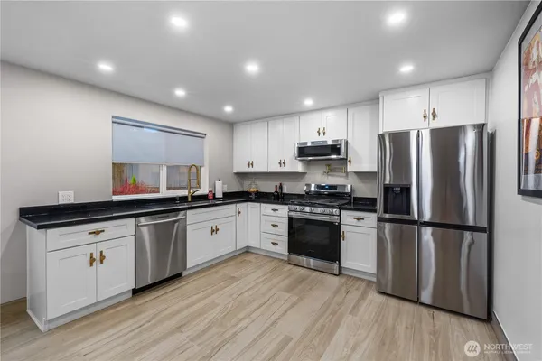 a kitchen with granite countertop a refrigerator stove top oven and sink