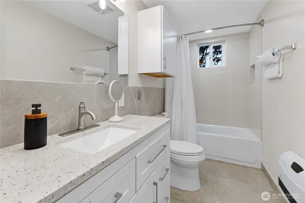 a bathroom with a granite countertop sink a toilet and shower