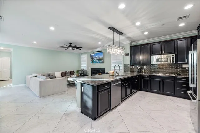 a kitchen with stainless steel appliances kitchen island granite countertop a table chairs and a refrigerator