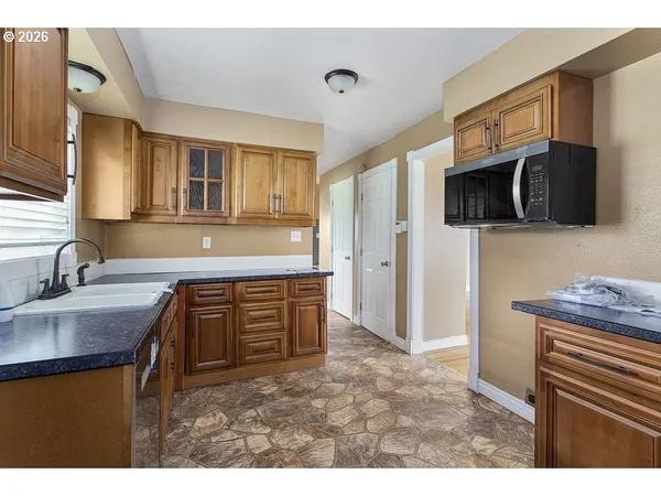 a kitchen with granite countertop a sink a stove a microwave a refrigerator a counter space and cabinets