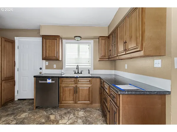 a kitchen with granite countertop a sink cabinets and stainless steel appliances