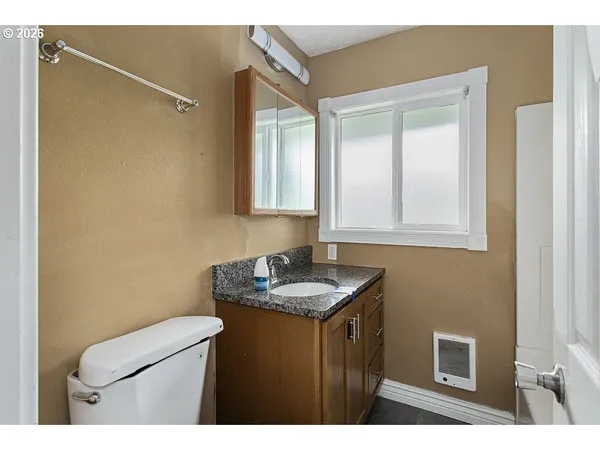 a bathroom with a granite countertop sink toilet and mirror