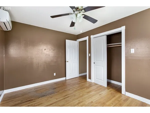 a view of an empty room with window and wooden floor