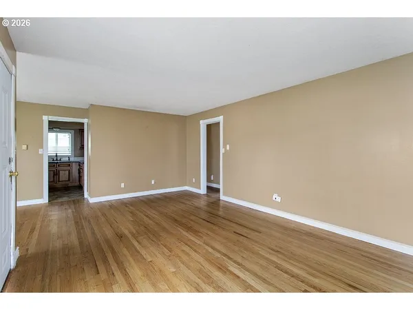 a view of an empty room with wooden floor and closet