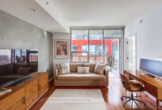 a living room with furniture a flat screen tv and a floor to ceiling window