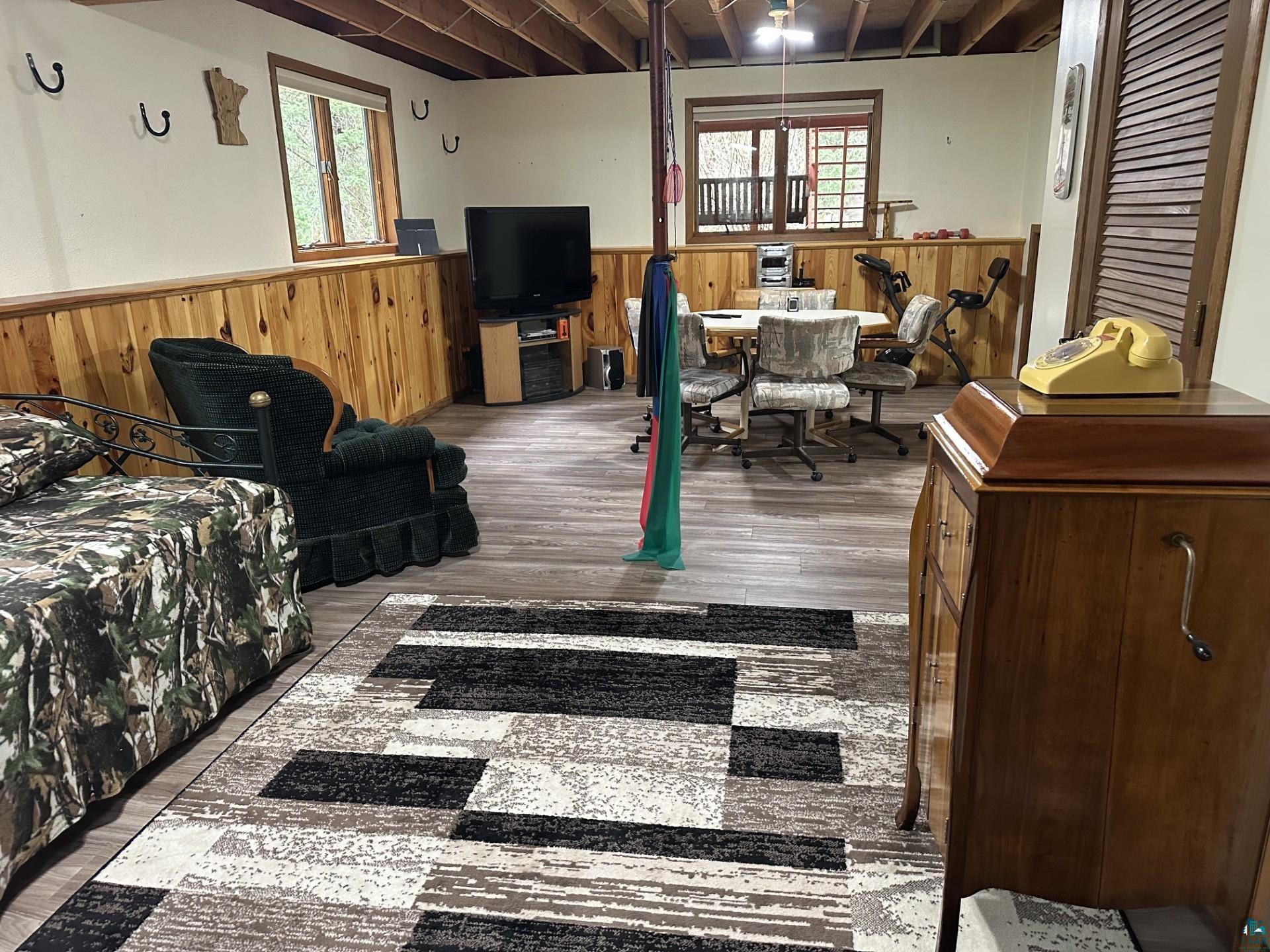 81 Hautaluoma Road Esko, MN 55733 - Photo 30 of 43 Lower level room featuring wood-finish flooring, wood paneling, and an exposed beam ceiling