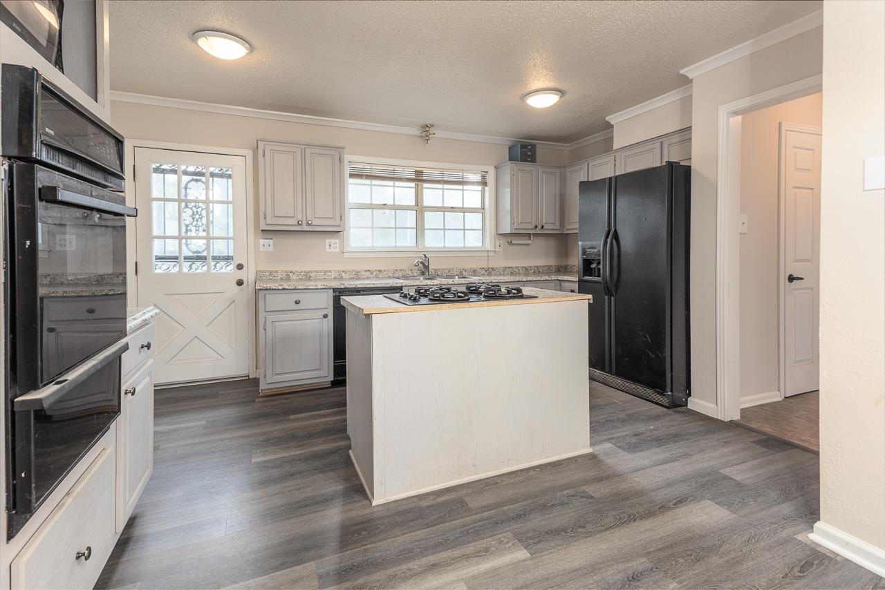2718 Kate Bond Road Memphis, TN 38133 - Photo 8 of 39 Kitchen with light countertops, a textured ceiling, black appliances, a center island, and dark wood-style floors