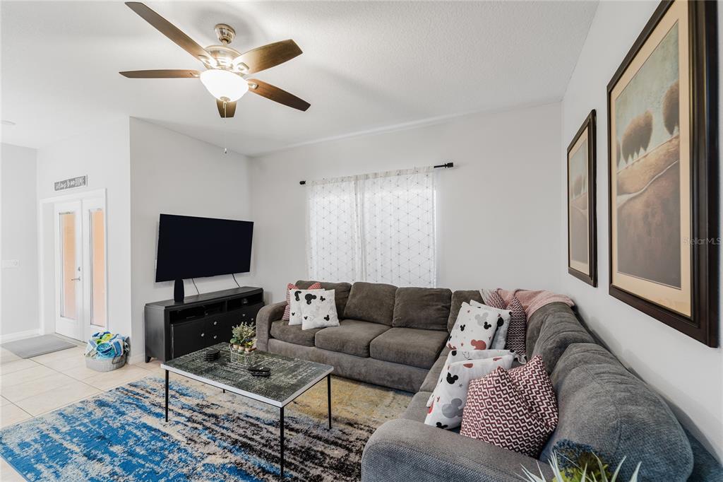 8961 Majesty Palm Road Kissimmee, FL 34747 - Photo 15 of 40 a living room with furniture a ceiling fan and a flat screen tv