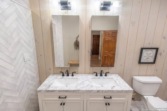 a white toilet sitting next to a bathroom sink and a mirror